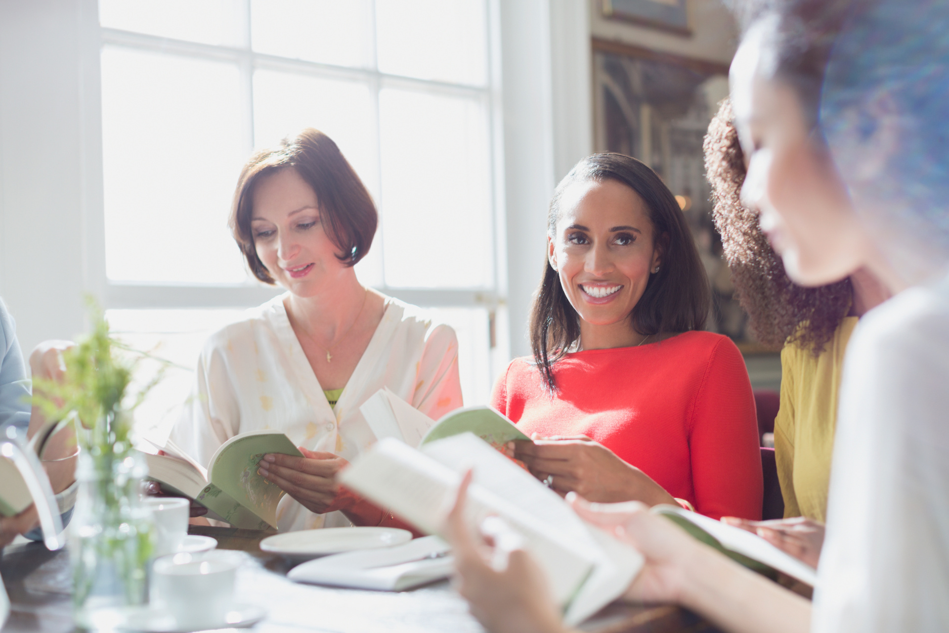 Women friends discussing book club book at restaurant table