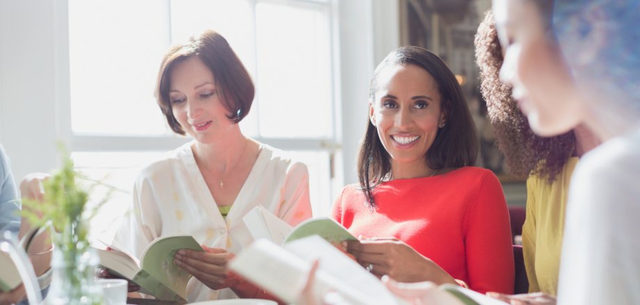 Women friends discussing book club book at restaurant table Women friends discussing book club book at restaurant table